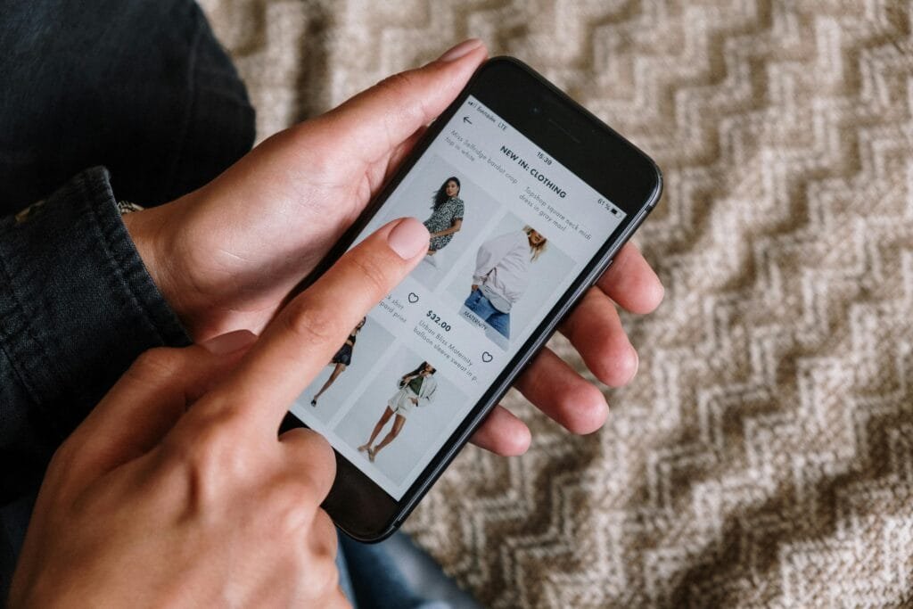 Person browsing clothing items on a smartphone, showcasing modern online shopping experience.