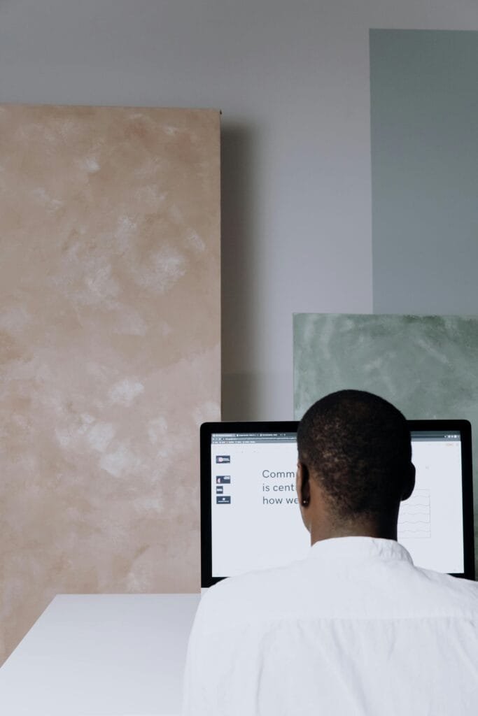 Back view of a man working at a computer in a modern office setting. Ideal for business themes.