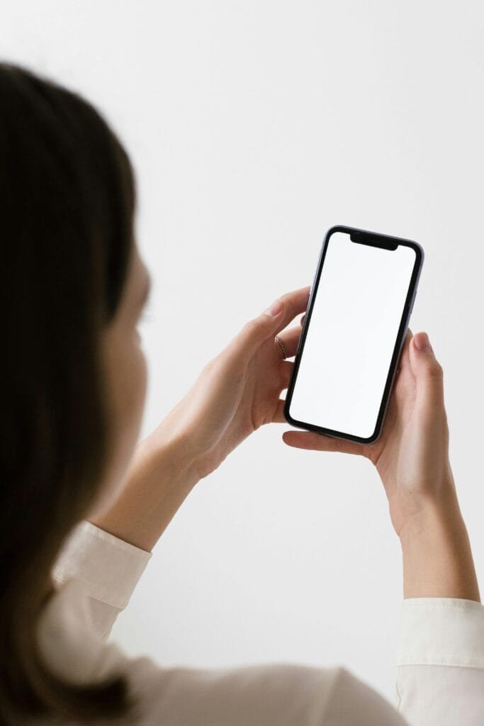 Female hand holding a smartphone with a blank screen suitable for app or website mockup.