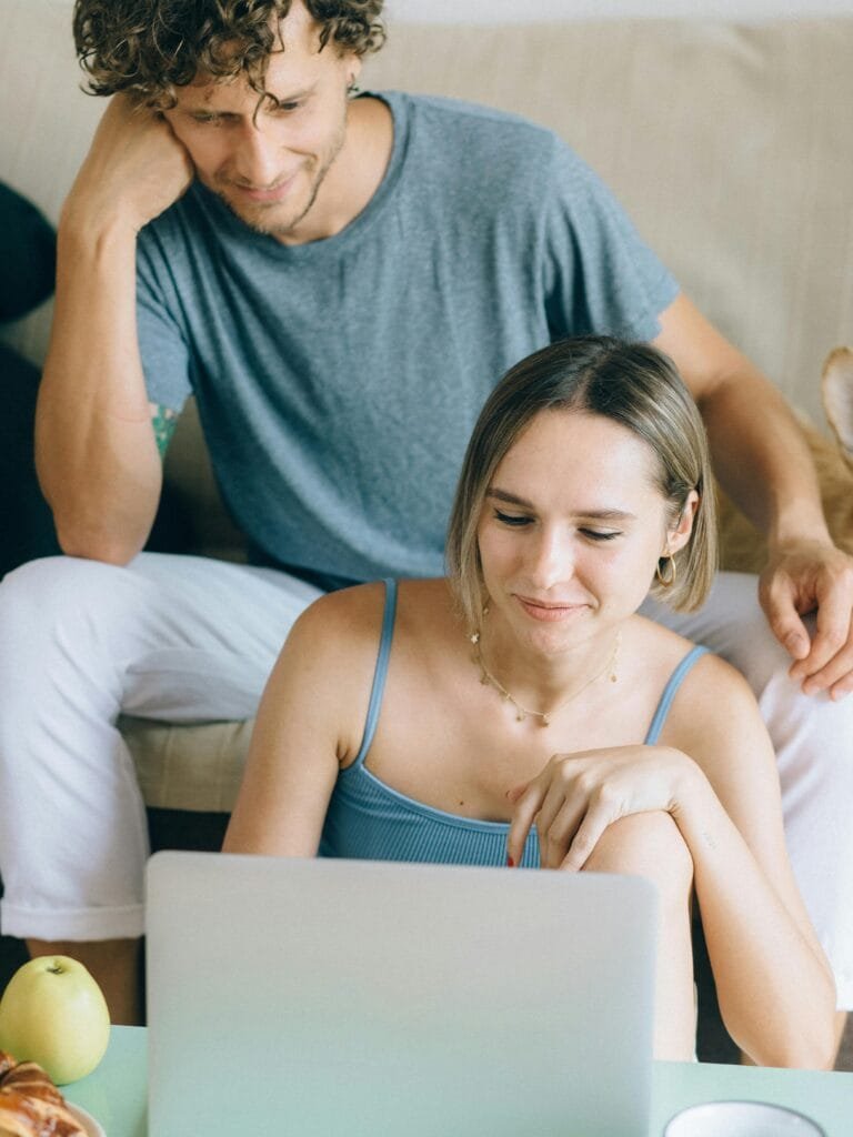 pexels-photo-8939555-8939555 A couple sitting on a sofa browsing a laptop, showcasing online shopping leisure.